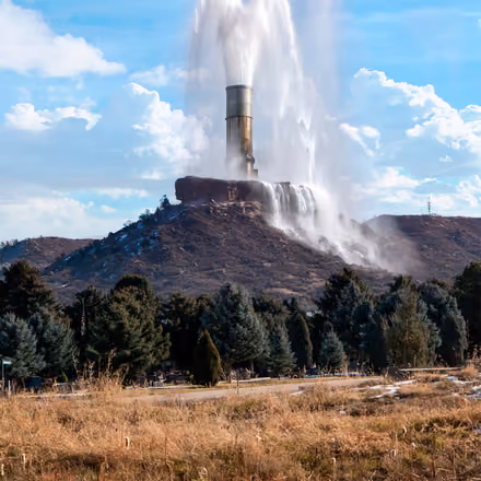 Castle Rock’s rock formation with a giant water pipe spouting from its top, above the trees