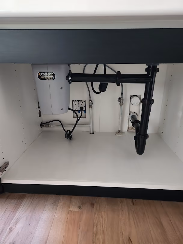 New black drain lines under a kitchen sink