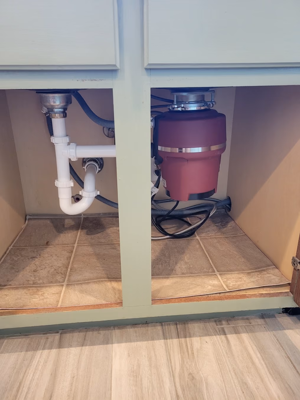 A garbage disposal and new drain lines under a sink