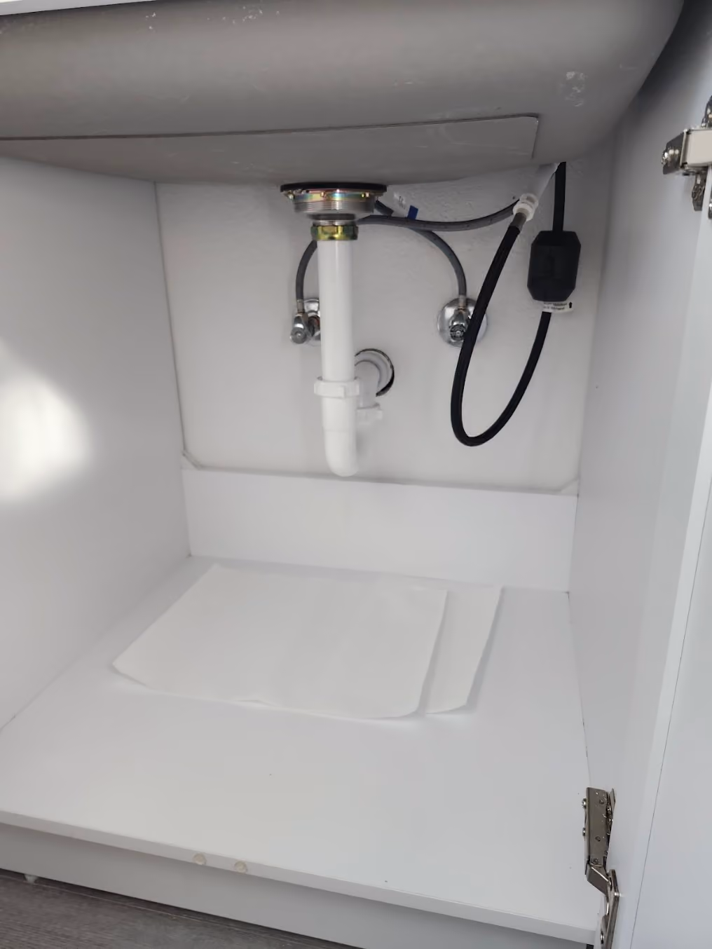 A new drain under a sink, beside the disposal's power cord