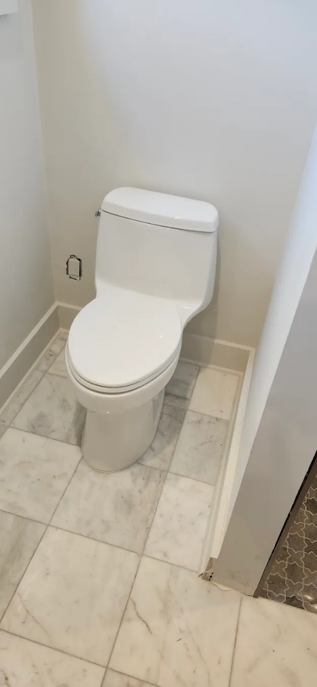A one-piece toilet in a marble-tiled bathroom.