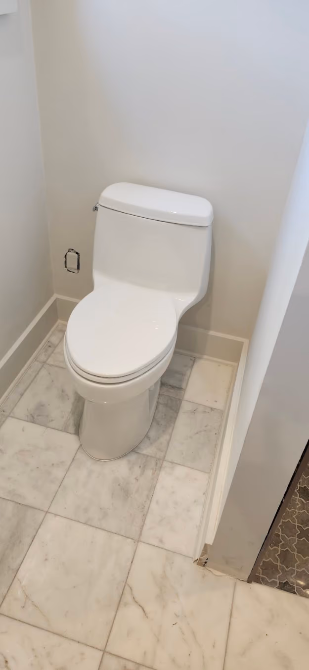 A one-piece toilet in a marble-tiled bathroom