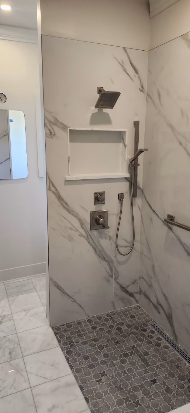 A shower valve and hand shower in a marble shower