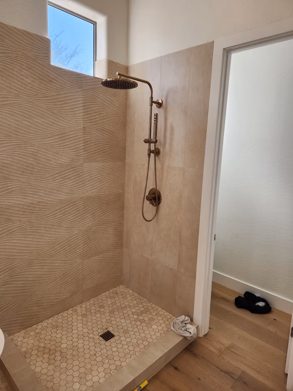 A walk-in shower with a rain head and hand shower