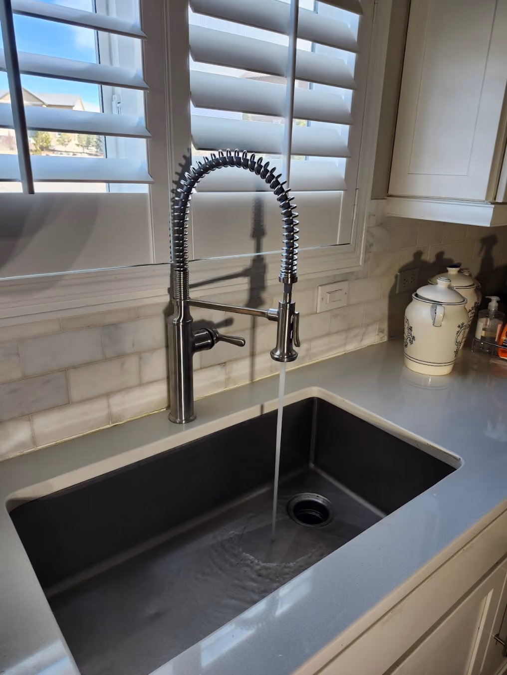 A pull-down faucet over a black granite sink