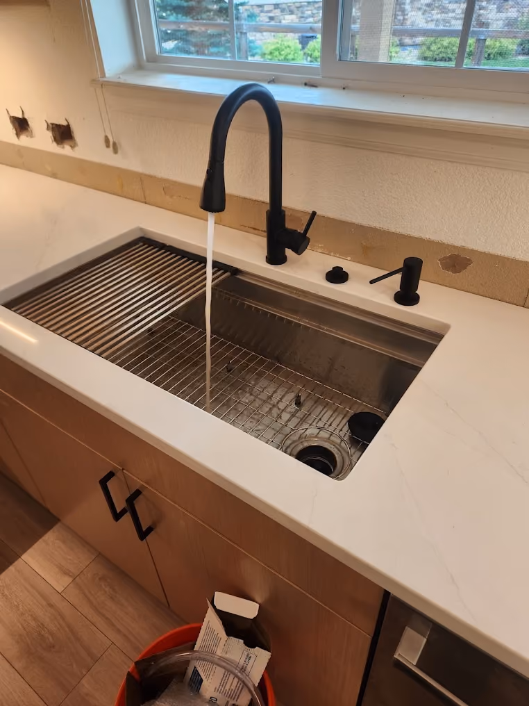 A black pull-down faucet over a workstation sink