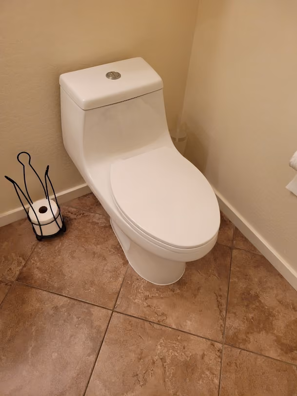 A one-piece toilet on a tile floor