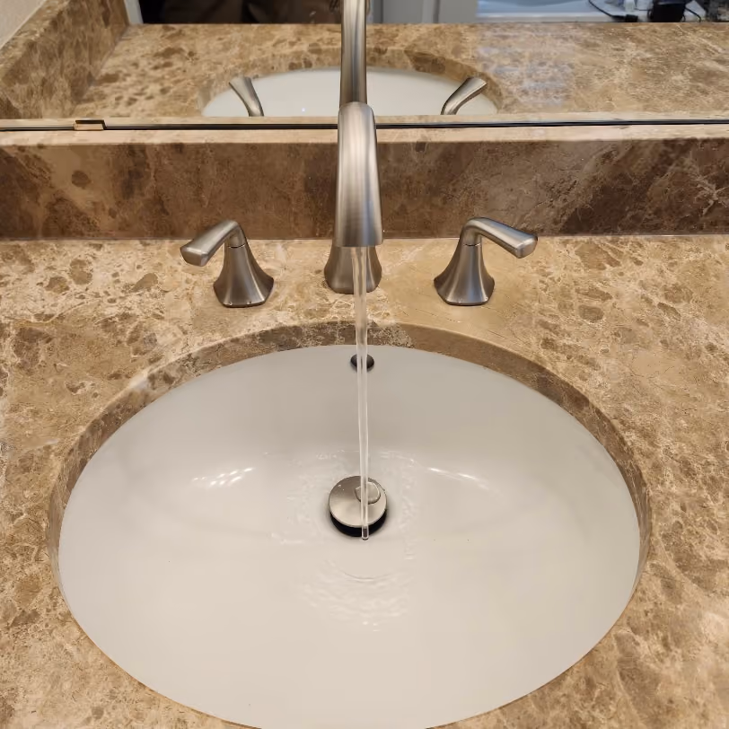 A bathroom faucet running into an oval sink