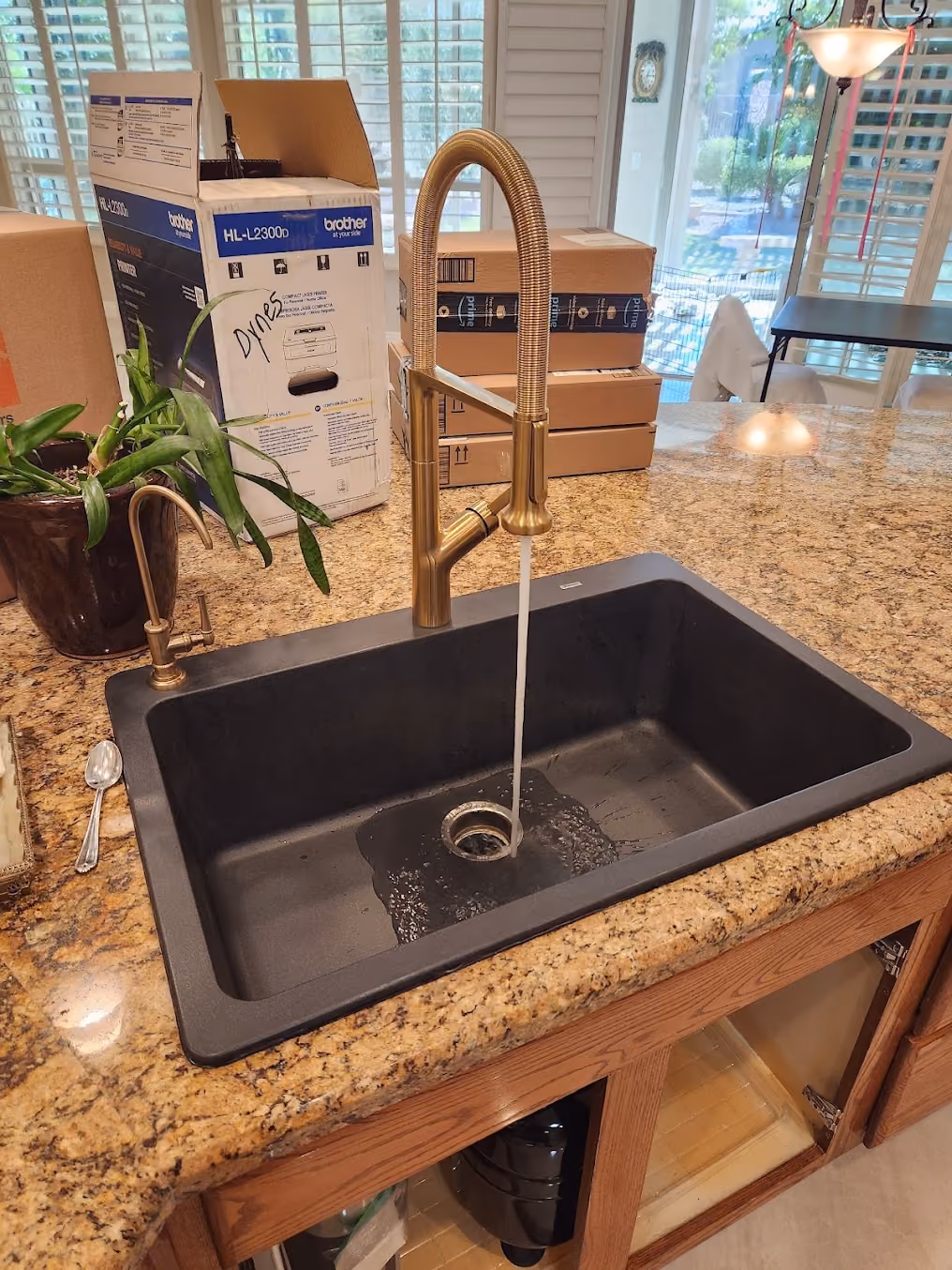 A brass faucet over a black granite sink