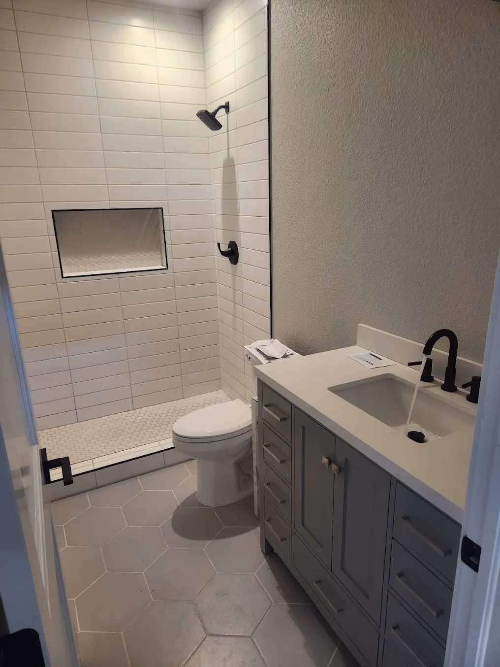 A remodeled bathroom with a new vanity, toilet and tiled shower