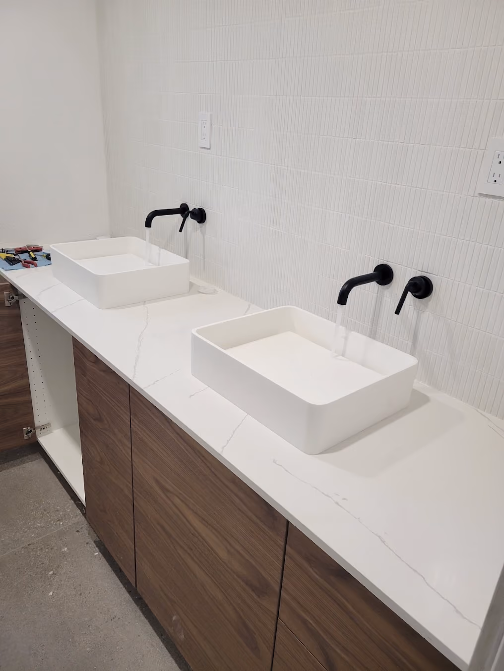 Two vessel sinks with wall-mounted black faucets