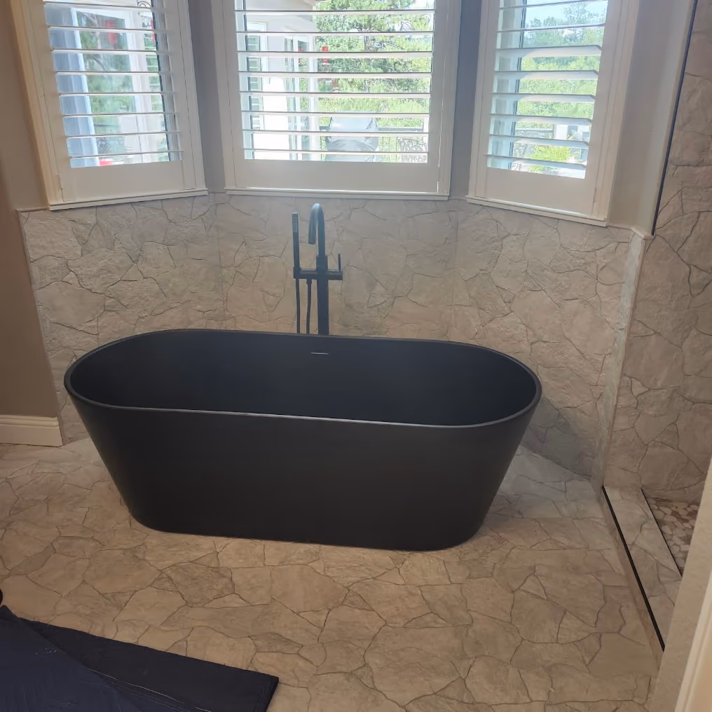 A black freestanding tub with a floor-mounted filler