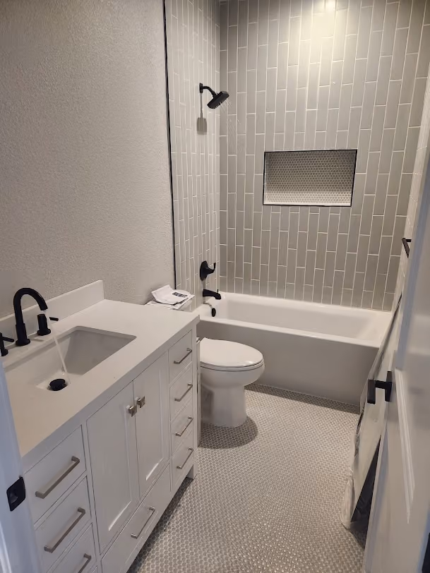 A remodeled bathroom with a new vanity, toilet and tub