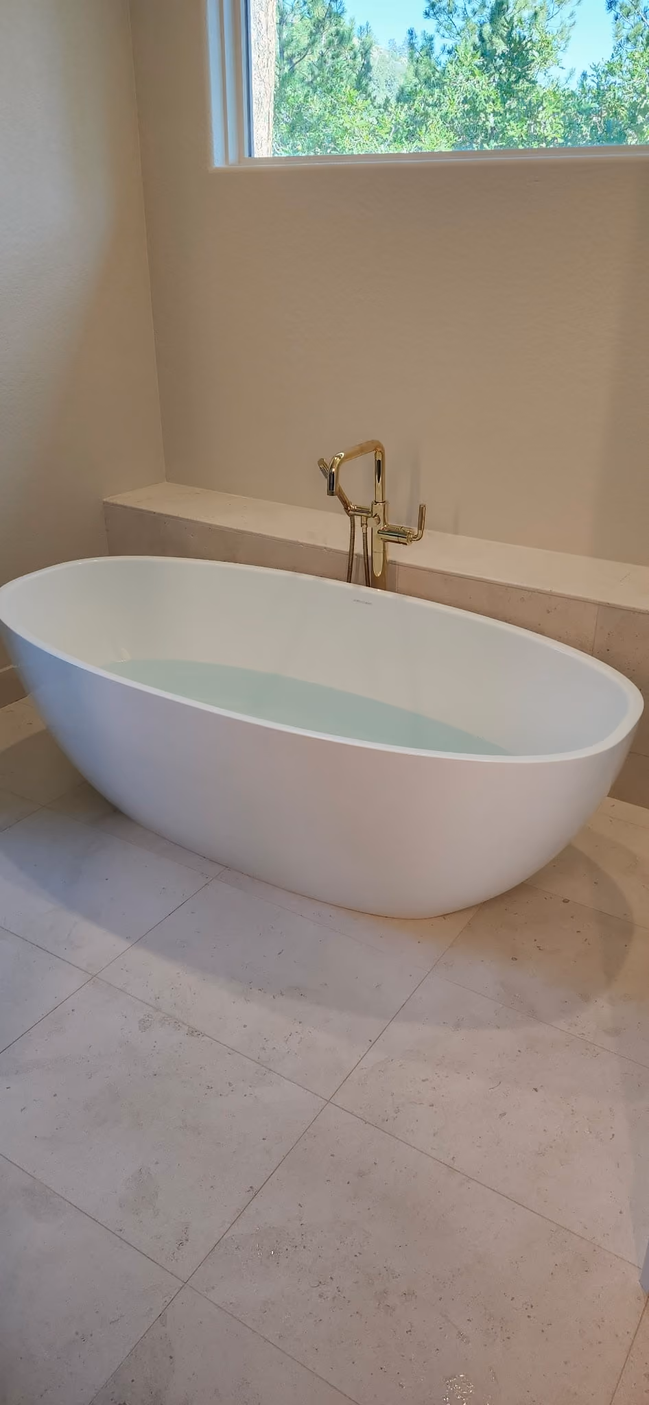 A freestanding tub with a brass floor-mounted filler
