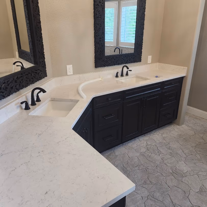 A corner double vanity with black faucets