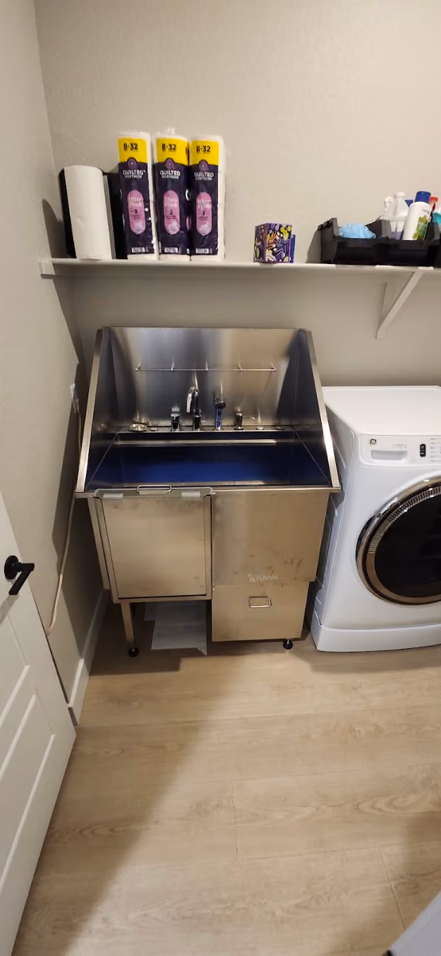 A stainless laundry sink beside a washer
