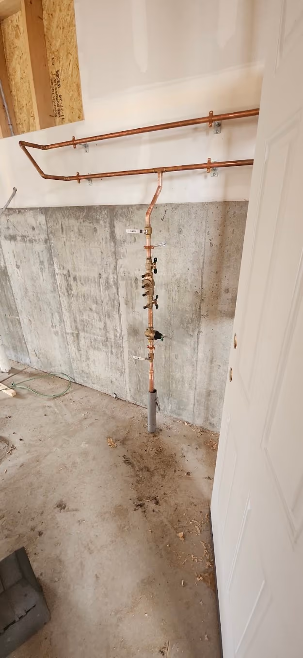A new copper water line rising through an unfinished basement