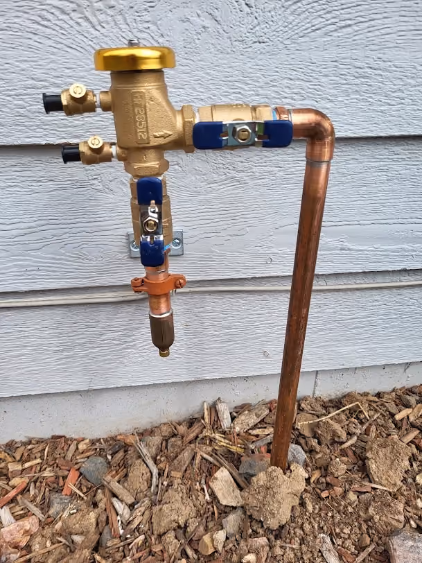 A new backflow preventer with copper piping, outside a house