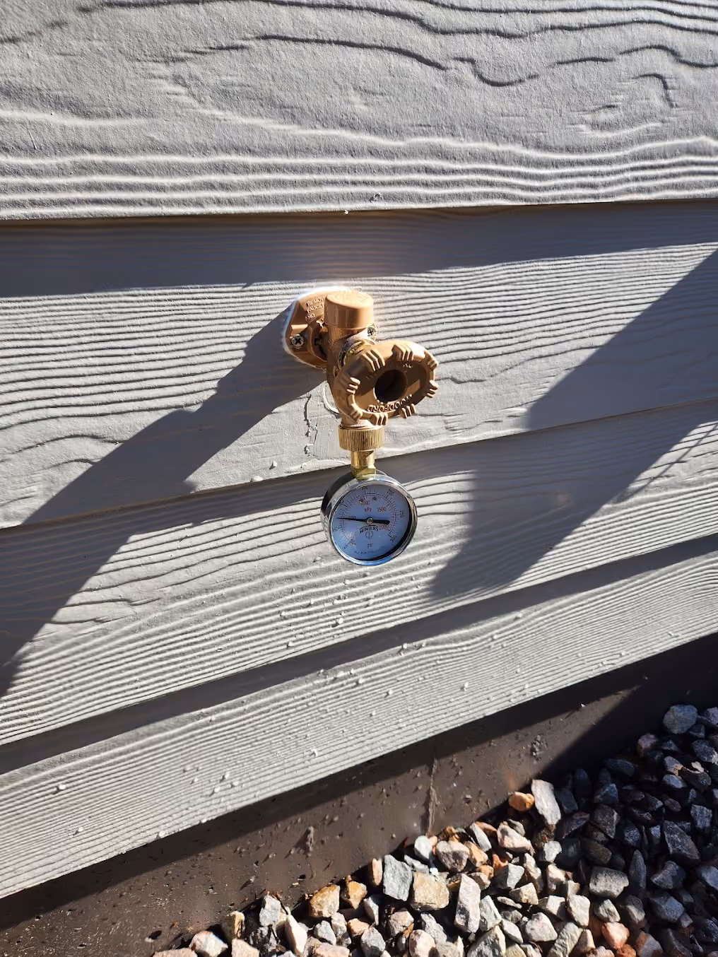 A pressure gauge on an outside faucet, checking the house's water pressure