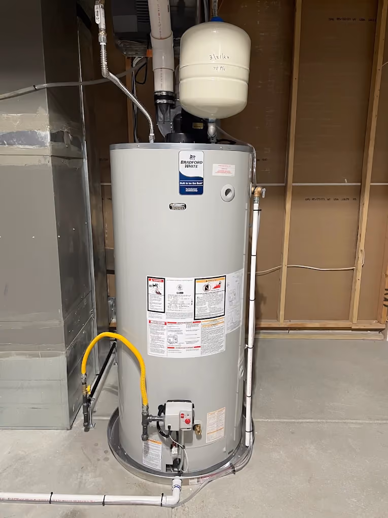 A newly installed gas water heater with an expansion tank and new supply lines