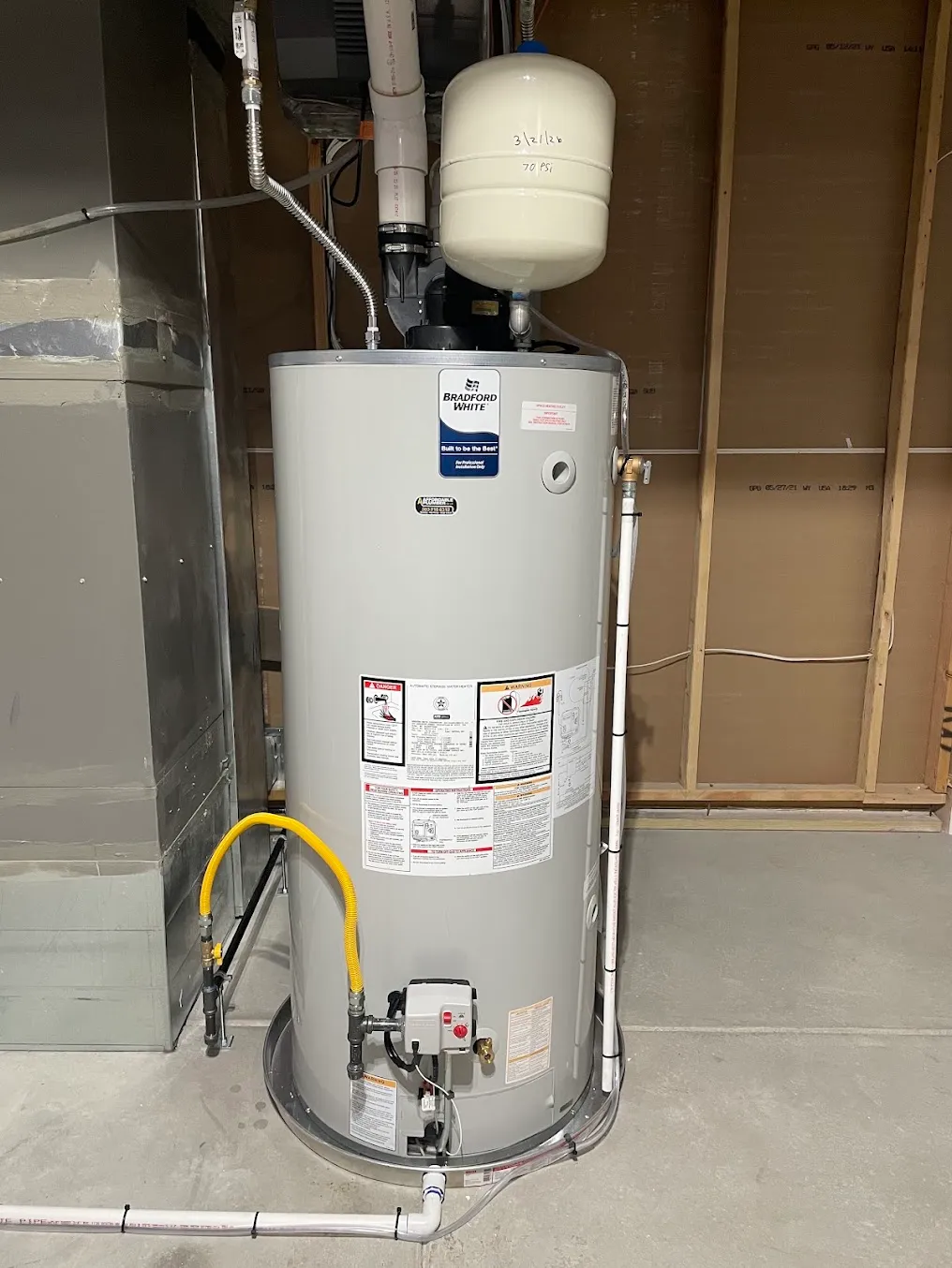 A new gas water heater with an expansion tank in a finished utility room.