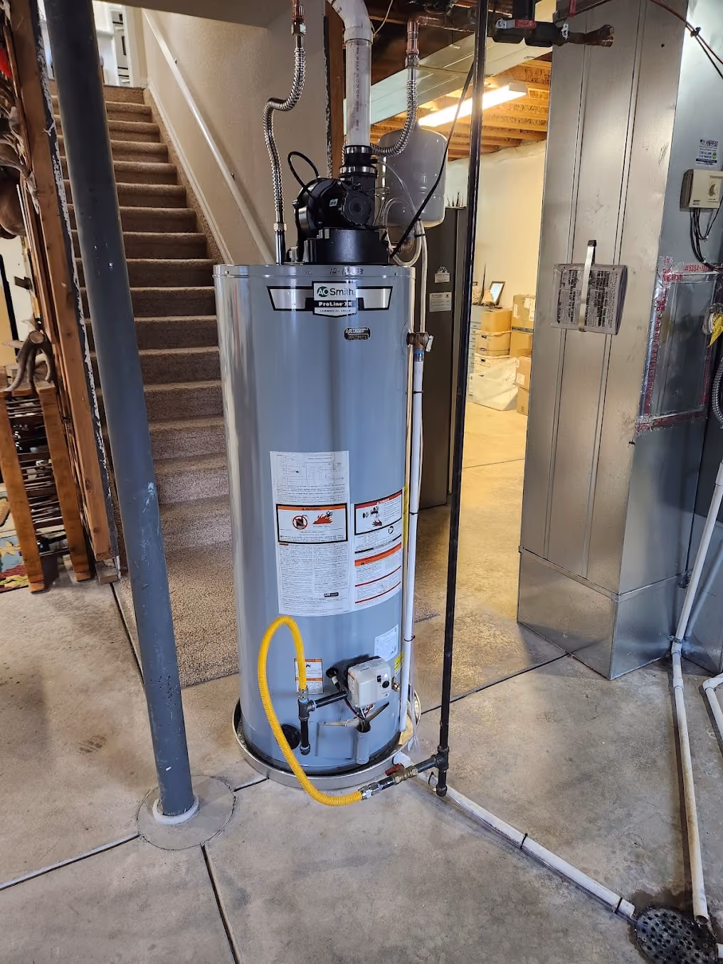 A gas water heater beside a basement stairway, with new venting