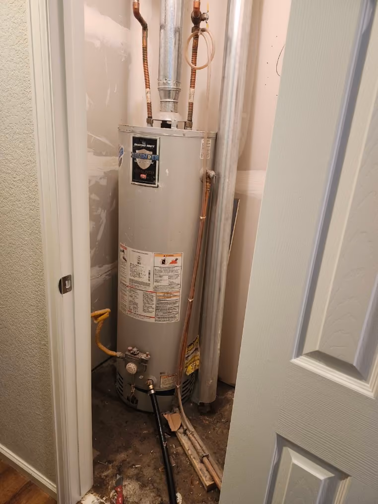 A gas water heater in a closet, with a sediment trap on the gas line