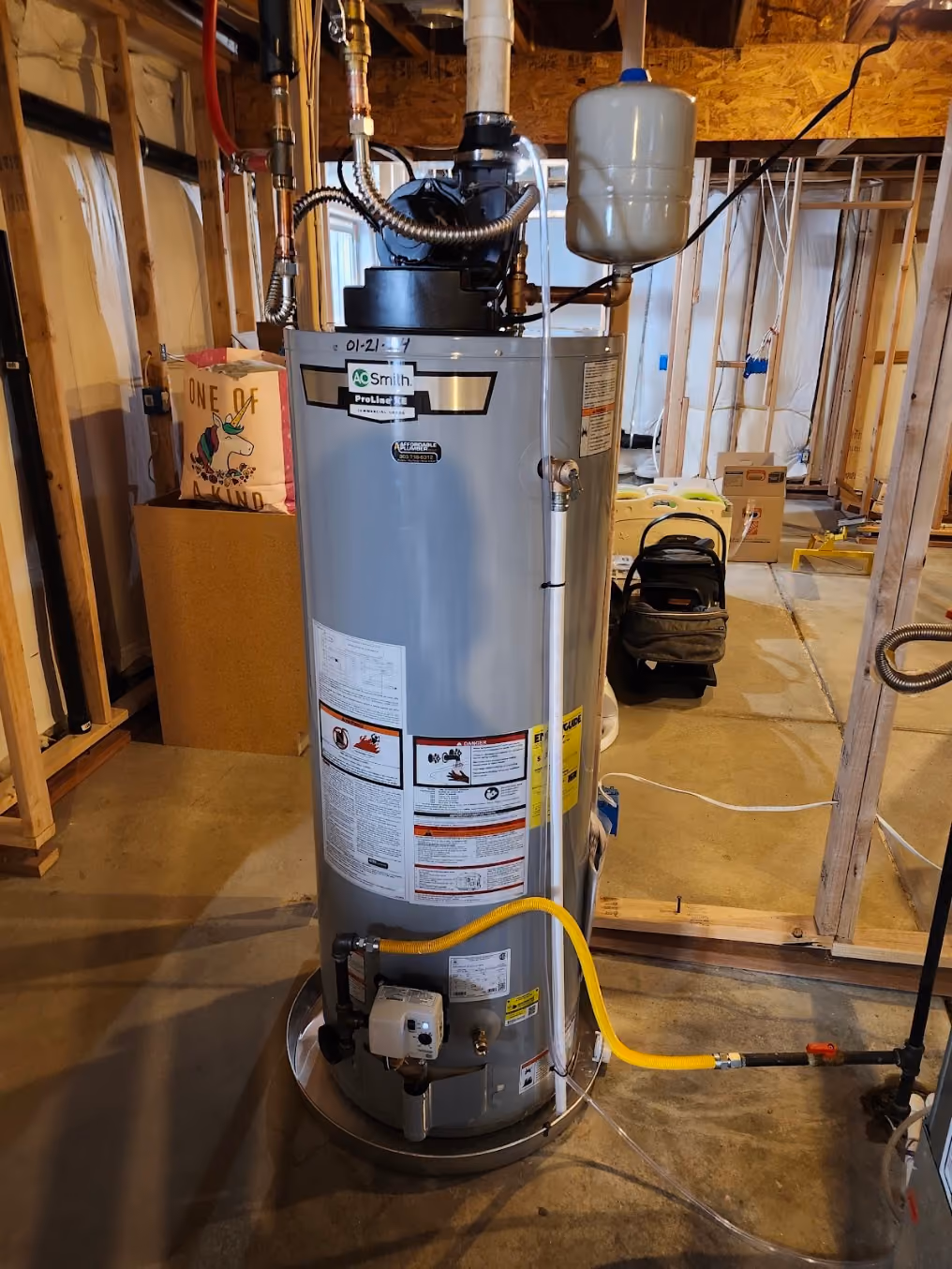 A tall gas water heater in a basement under construction