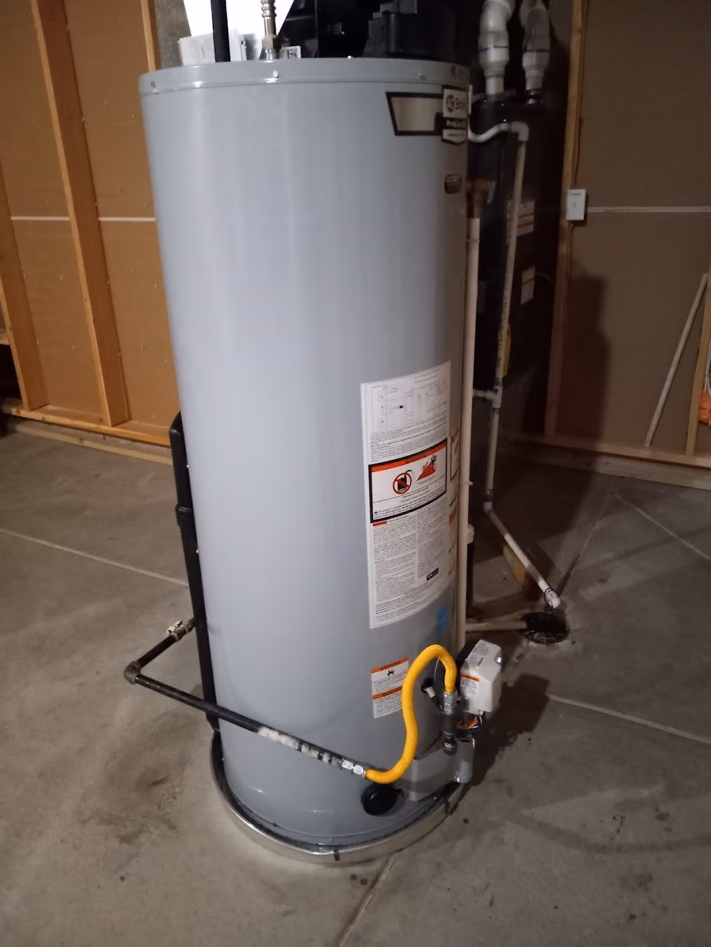 A water heater with a new gas connection, beside an unfinished wall